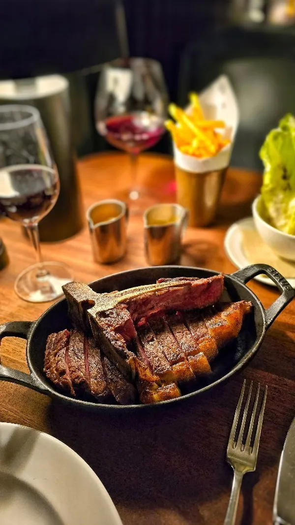 The video showcases a meal at the Hawksmoor Knightsbridge steakhouse.  It features various dishes: oysters on ice, a whole roasted lobster with lemon and herbs, and a porterhouse steak sliced and served in a cast iron dish.  The presentation is elegant and focuses on high-quality ingredients. There is no mention of dietary information. The main focus is on showcasing the food and dining experience at the restaurant.