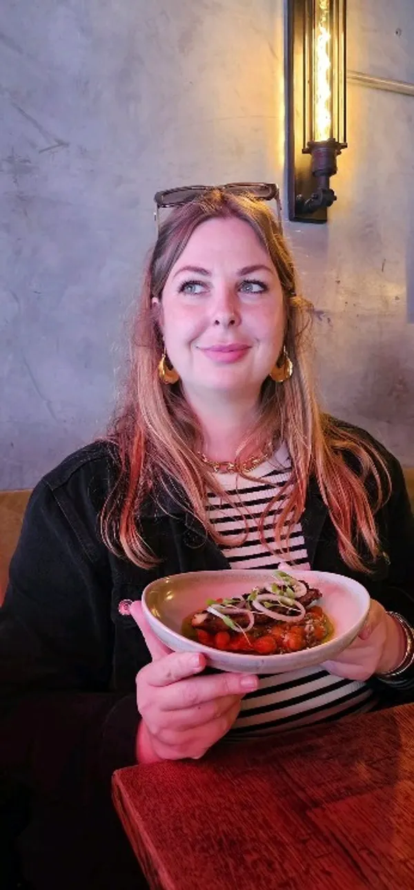 The video showcases a meal at Ember Yard restaurant in Soho, London. It features various dishes from the tasting menu, including cocktails, roasted peppers, olives, prawns with croquettes, mackerel, asparagus with smoked almonds, heirloom tomatoes, Iberico pork secreto, smoked burrata with pea pesto, and a raspberry dessert. The food is presented attractively on plates, and many shots focus on close-ups of textures and colors. The cocktails are also featured prominently, with one person enjoying a cocktail at the table. The restaurant’s ambiance is visible throughout, with warm lighting and wooden furniture.