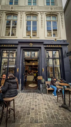 Enjoying Belgian fries with sauces and beer at Frites Atelier in Brussels, a must-visit for food lovers.