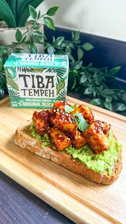 Harissa Tiba Tempeh Avocado Toast topped with sesame seeds, a vibrant brunch dish showcasing plant-based goodness.