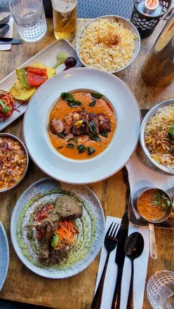 Diners enjoying signature duck curry and Peshwari lamb chops at Black Cumin in Bristol, perfect for curry lovers!