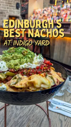 Friends enjoying giant nachos with cheese at Indigo Yard in Edinburgh, praised as the best in the city.