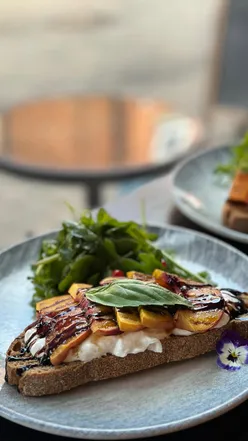 Brunch at Ovation Bar featuring small plates like smoothie bowls, avocado toast, and iced coffees in a cozy setting.