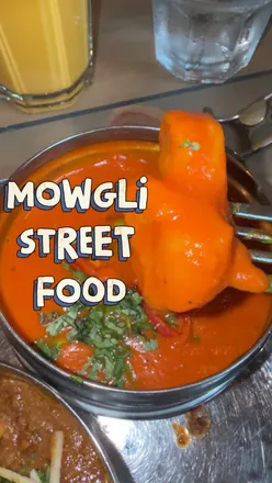 Guests enjoying vibrant Indian tapas at Mowgli Street Food on St Vincent Street, showcasing a lively venue and attentive service.