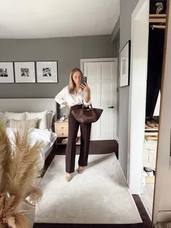 Fashionable woman in heels, coffee in hand, ready for a meeting but heading to Starbucks casually.