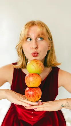 Self-portrait with apples in a garden, showcasing vibrant colors and textures, celebrating natural beauty and creativity.