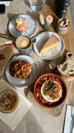 Artisan dishes and coffee at Faun Bakery & Café in Malvern, Worcestershire, featuring sausage sandwich and sweet treats.