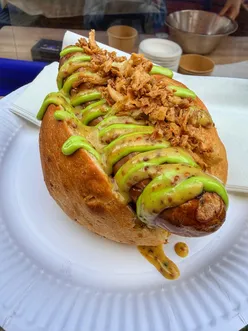 Bratwurst in onion bun with mustard from Flour 21 Microbakery at Oktoberfest celebration in Hitchin.