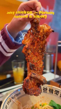 Visitors enjoying hand-pulled Belt Noodles topped with smoky chicken at Belt Noodles in London’s Chinatown.