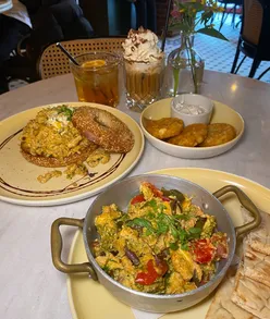 Enjoying a halal brunch featuring shakshuka, scrambled eggs, and tiramisu iced latte at Apple Butter Cafe in London.