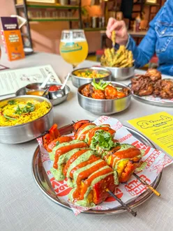 Vibrant street food at Bundobust Liverpool, featuring Chole Saag, Bundo Chaat, and craft beer, all 100% vegetarian.