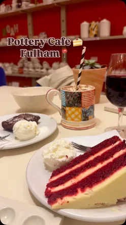 Two friends enjoying red velvet cake and hot chocolate at The Pottery Cafe in Fulham during an artistic evening.