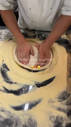 Visitors enjoying wood-fired Neapolitan pizza at Naples, Liverpool, featuring vegan options and delicious desserts.