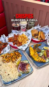 A fast-paced montage showcasing the menu at Crispies Burgers & Grill, featuring close-ups of burgers, wings, grilled chicken, rice dishes, and drinks, interspersed with shots of the restaurant interior.