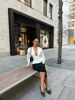 Model wearing Off Duty Boss Puff Sleeve Button Front Blouse at a stylish cafe with a coffee.