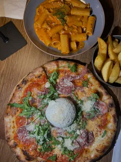 Couple enjoying Italian dishes at The Riverside, including arancini, polpette, and a delicious burrata pizza.