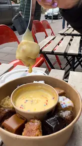 A short promotional video showcasing the 'Double Dipper' dessert platter at The Cuppie Hut in Norwich, featuring various cakes served with a pot of warm custard.