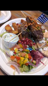 A short promotional video for The Gyros Place located in an indoor market, featuring shots of the exterior, the menu, and close-ups of various Greek dishes including lamb kofte, gyros, and loaded fries.