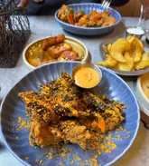 A high-angle, appetizing shot of a table spread featuring loaded chicken strips, halloumi bites, and fries at a restaurant.