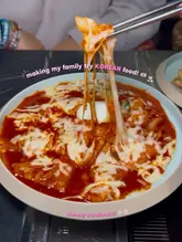 A close-up, high-engagement shot of a cheese-topped tteokbokki dish being lifted with chopsticks, effectively capturing the texture and indulgence of the food.