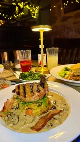 A montage of food and drink items served at a pub, featuring a pork chop dish, a pie, and a cheese board.