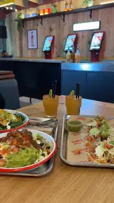 A short, energetic vlog-style video showcasing the opening of a new Tortilla restaurant in Leeds. The video features the creator trying various dishes, including burrito bowls and tacos, as well as spicy margarita slushies. It highlights the venue's interior, the ordering counter, and the lively atmosphere with a DJ.