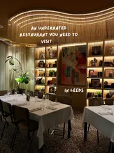 A well-composed, warm, and inviting interior shot of a restaurant in Leeds, showcasing the elegant decor and table settings.