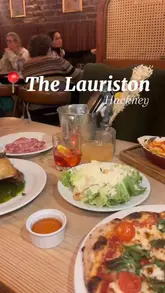 A montage-style video showcasing a dinner visit to The Lauriston in Hackney, featuring shots of the interior, the menu, various starters, mains, and desserts.