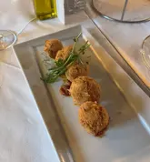 A top-down shot of fried mozzarella balls served on a rectangular plate in a restaurant setting. The image captures the food clearly but is let down by distracting background clutter and uninspired plating.