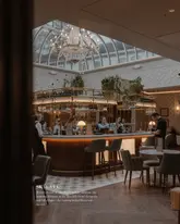A wide-angle shot of the interior of Skylark Brasserie at The Marcliffe Hotel, highlighting the central bar and the large, light-filled skylight above.