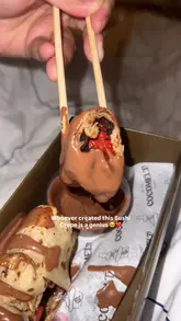 A short, handheld video showcasing a 'sushi crepe' dessert from Cocomelt London, featuring a close-up of the crepe being dipped into chocolate sauce.