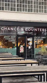 A short video showcasing Chance & Counters, a board game cafe. The footage includes the exterior, the extensive library of board games, a child playing a game, and close-ups of the food and drink menu and served items like burgers and loaded fries.