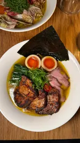 A vlog-style review of a ramen pop-up residency called Robin's Ramen at Supermarket of Dreams in London. The creator highlights the quality of the broth and pork belly, noting the affordable price point and the open kitchen setting.