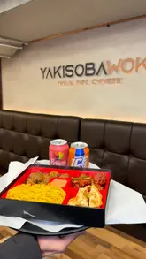 A promotional video showcasing a bento-style meal box from Yakisobawok, featuring Indo-Chinese dishes like noodles, dumplings, and chicken, presented in a casual dining setting.