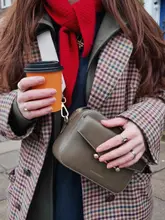 A high-quality, well-composed fashion-focused lifestyle shot featuring a person holding a coffee cup and a designer handbag, emphasizing outfit details. The image is clean, sharp, and professionally styled, serving as a lifestyle aesthetic post rather than a hospitality venue promotion.