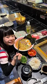 A short, vlog-style video featuring a young girl enjoying a meal at High Yaki, a restaurant in London's Chinatown. The video showcases the interactive nature of the dining experience, specifically the tabletop BBQ, alongside a bowl of ramen.