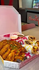 A food showcase video featuring a large sharing box from Rounders, containing fried chicken, wraps, smashed beef, masala fries, and sides, followed by a mango milkshake and gulab jamun with ice cream.