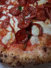A close-up, top-down shot of a pepperoni pizza, focusing on the texture of the cheese and the char on the meat.