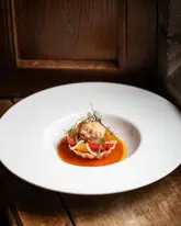 A high-end, professionally captured image of a delicate crab tartlet, showcasing precise plating and sophisticated culinary presentation against a rustic wooden background.