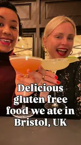 A vlog-style reel featuring two creators exploring various gluten-free dining spots in Bristol, including a dim sum restaurant, a fried chicken and waffle spot, a taco stand, and a donut shop.