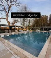 A serene, symmetrical shot of the outdoor swimming pool at Middleton Lodge Spa during twilight. The image effectively captures the tranquil and upscale atmosphere of the venue, using natural light to create an inviting mood.
