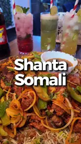 A montage of close-up shots focusing on a large Somali sharing platter featuring lamb, chicken, and beef, along with shots of soup and drinks at Shanta Somali.
