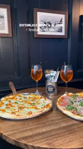 The video is a short, edited montage showcasing a bottomless brunch experience at Newhall Street Tavern. It features shots of pizzas, cocktails, and the venue's shuffleboard facilities, highlighting the combination of food and competitive socialising.