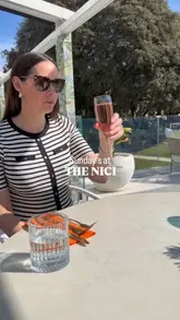 Outdoor dining at The Nici: couple enjoys Sunday lunch with beer and sparkling rosé by the pool and gardens.