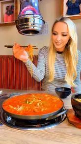 A video review of Ban Di Bul in Liverpool, showcasing their Korean seafood hotpot which is cooked at the table, along with various side dishes like chicken teriyaki skewers and kimchi.
