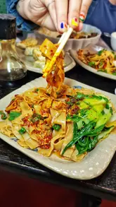 A short-form video review of 'Eat & Sip Market', a small eatery located inside an Asian grocery store in Cardiff. The video features close-up shots of various Chinese dishes, including noodles, dumplings, bao, and omurice, alongside shots of the grocery store aisles, effectively showcasing the unique 'hidden gem' atmosphere.