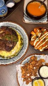 A short, engaging reel showcasing a visit to Lírica, a Spanish restaurant located inside The Cumberland Hotel in London. The video follows the creator as they enter the hotel, walk through the space, and sample a variety of dishes including patatas bravas, gazpacho, rib eye steak, churros, and Basque cheesecake.