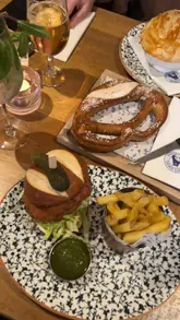 A short montage video capturing a visit to Albert's Schloss in Liverpool, featuring shots of the venue's interior, the menu, drinks, and food items like a halloumi schnitzel burger and a pretzel.