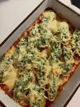 A top-down shot of a baking dish filled with spinach and ricotta stuffed pasta shells in a tomato sauce, topped with melted cheese.