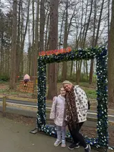 A candid photo of a woman and child posing under a floral archway at Stockeld Park, with a woodland background. The image serves as a promotional snapshot for a family day out.